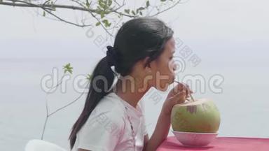 一位亚洲女人喝新鲜椰子汁的户外特写夏季肖像。